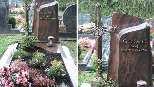 Gedenkstätte mit geschwungenen Platten aus Granit, rot und dunkelgrau, mit Bronzekreuz.